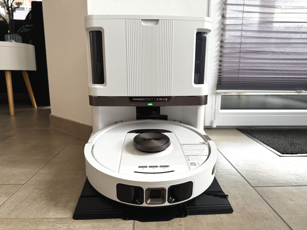 Der Shark PowerDetect NeverTouch Pro 2-in-1 Saug- und Wischroboter steht in seiner vollautomatischen Reinigungsstation. Das Modell in Weiß mit silbernen Akzenten ist dezent designt und fügt sich nahtlos in moderne Wohnräume ein. (Foto: Testsieger.de)